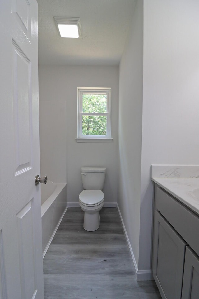 8305 Utopia Ln, East Stroudsburg, PA 18302 - full bath featuring toilet, vanity, a tub to relax in, wood finished floors, and baseboards