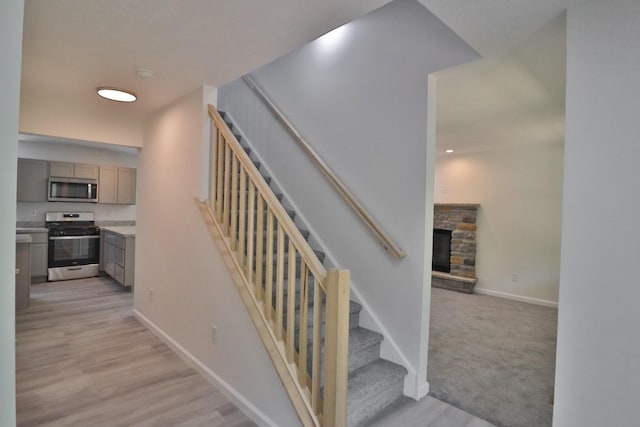 8305 Utopia Ln, East Stroudsburg, PA 18302 - stairs featuring baseboards, a stone fireplace, and wood finished floors