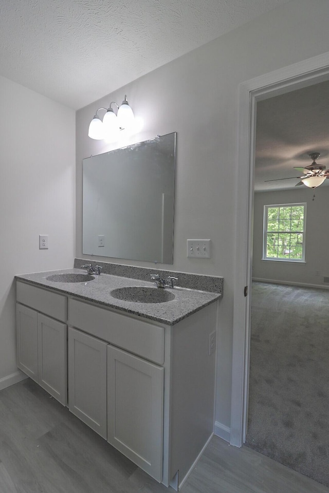 8305 Utopia Ln, East Stroudsburg, PA 18302 - full bathroom with double vanity, a ceiling fan, baseboards, wood finished floors, and a textured ceiling