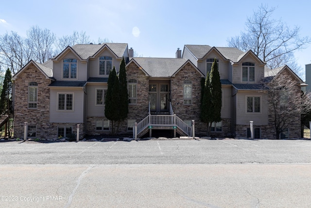 view of front facade with stone siding and a chimney