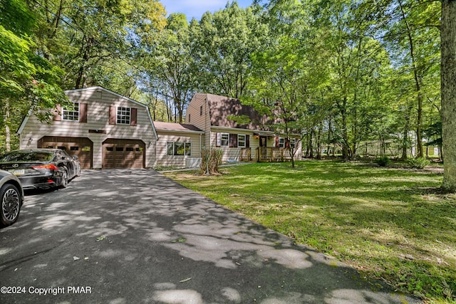 view of front facade featuring driveway, a gambrel roof, an attached garage, a front lawn, and a porch