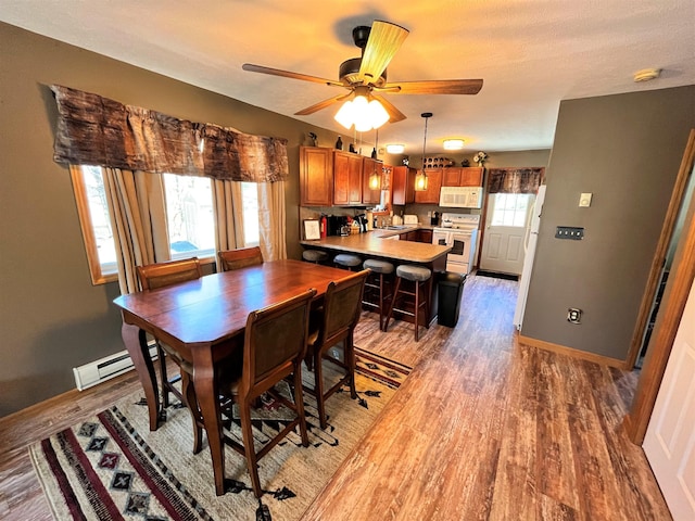 dining space featuring light wood-type flooring, baseboards, and ceiling fan