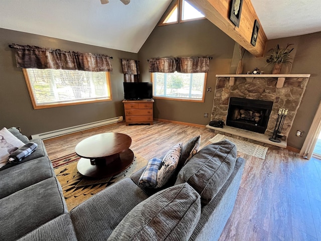 living area featuring a stone fireplace, a baseboard radiator, wood finished floors, and a wealth of natural light