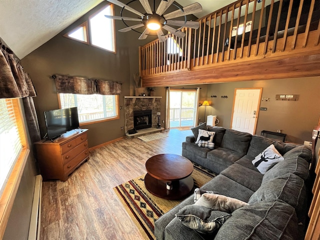 living room with wood finished floors, a fireplace, baseboards, ceiling fan, and high vaulted ceiling