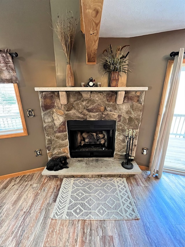 interior details with a stone fireplace, baseboards, and wood finished floors