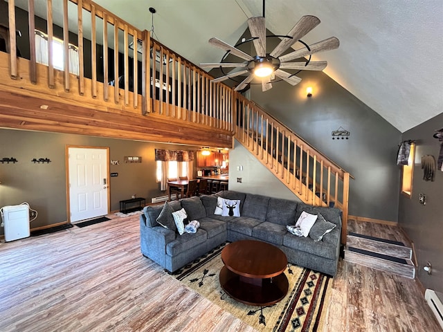 living room with stairs, a ceiling fan, baseboards, wood finished floors, and a baseboard radiator