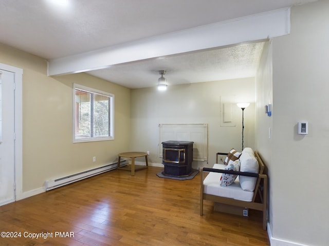 sitting room featuring a baseboard radiator, wood finished floors, a wood stove, and baseboards