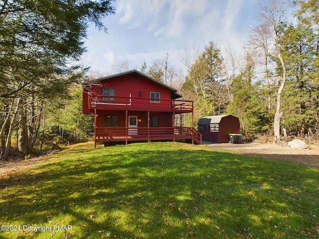 rear view of property with a wooden deck, an outdoor structure, and a yard