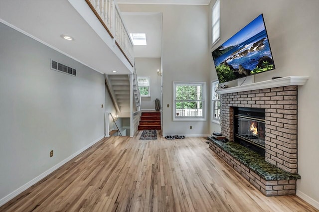 14 Ace Ln, East Stroudsburg, PA 18301 - unfurnished living room featuring wood finished floors, a brick fireplace, baseboards, a high ceiling, and stairway