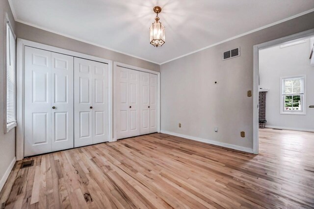 14 Ace Ln, East Stroudsburg, PA 18301 - unfurnished bedroom with light wood-style flooring, multiple closets, a chandelier, baseboards, and crown molding
