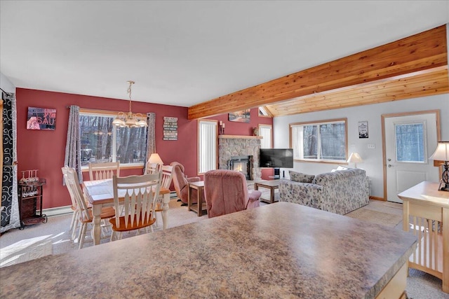 dining space featuring a chandelier, light colored carpet, a fireplace, and baseboards