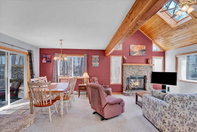 carpeted living room featuring a baseboard radiator, a notable chandelier, a fireplace, baseboards, and lofted ceiling with skylight