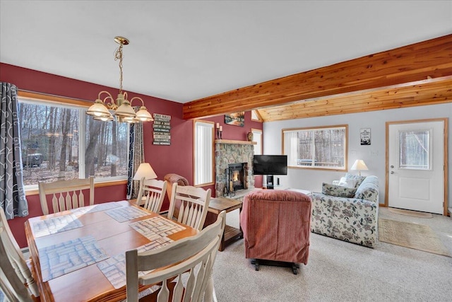 dining space with light carpet, vaulted ceiling with beams, a chandelier, and a stone fireplace