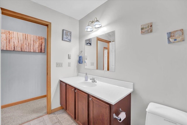 half bath with toilet, baseboards, and vanity