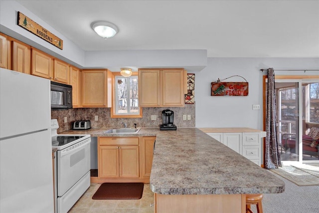 kitchen featuring a peninsula, white appliances, light brown cabinets, and a sink