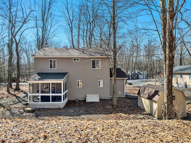 rear view of property with an outbuilding, a sunroom, and a storage shed