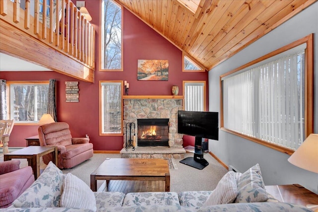 carpeted living area with high vaulted ceiling, wooden ceiling, a stone fireplace, and baseboards