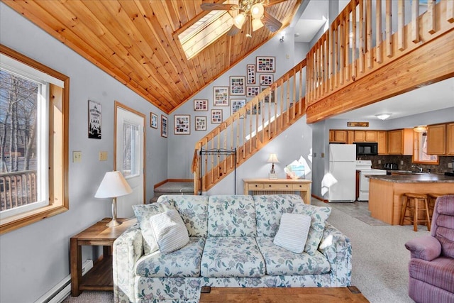 living room with a skylight, a ceiling fan, light colored carpet, wooden ceiling, and stairs