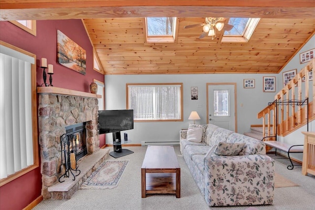 living room featuring lofted ceiling with skylight, a baseboard radiator, stairway, carpet flooring, and a fireplace