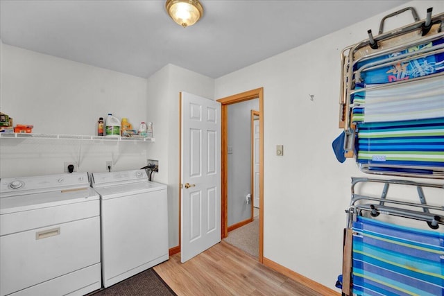 clothes washing area featuring laundry area, baseboards, light wood finished floors, and washing machine and clothes dryer