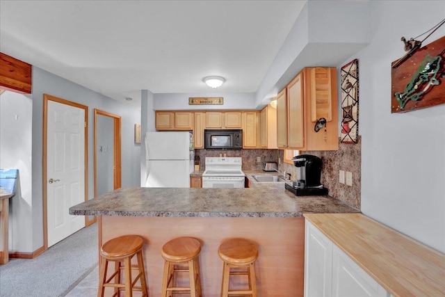 kitchen featuring a peninsula, white appliances, a sink, a kitchen breakfast bar, and tasteful backsplash