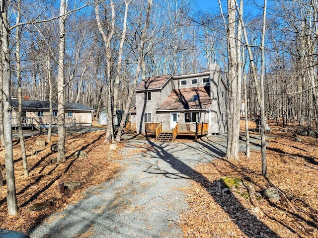 view of front of home featuring driveway, a chimney, and a wooden deck