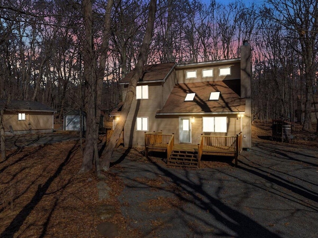 view of front of home featuring a storage shed, a chimney, a deck, and an outdoor structure