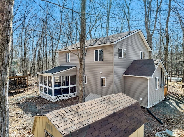 back of house with a shingled roof and a sunroom