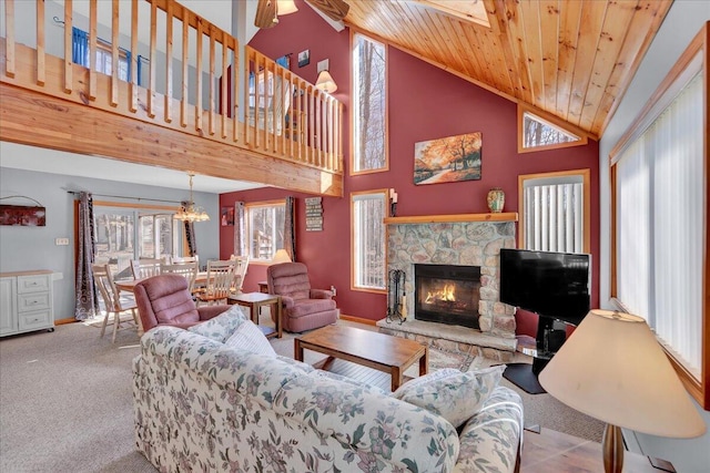 living area with wood ceiling, carpet flooring, a stone fireplace, and baseboards