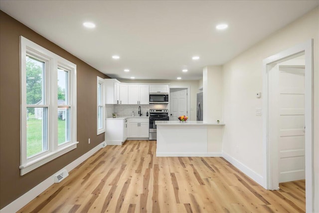 428 Shook Ave, Stroudsburg, PA 18360 - kitchen featuring appliances with stainless steel finishes, light wood-style floors, light countertops, white cabinets, and decorative backsplash