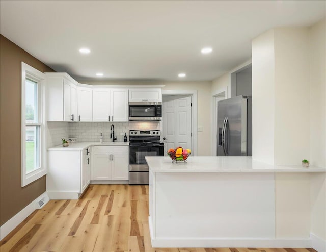428 Shook Ave, Stroudsburg, PA 18360 - kitchen featuring stainless steel appliances, a peninsula, decorative backsplash, light wood-type flooring, and white cabinets