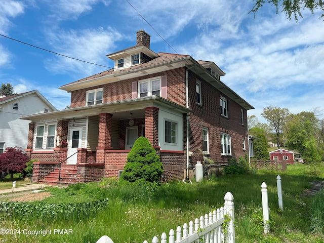 traditional style home featuring a porch, brick siding, fence, and a chimney