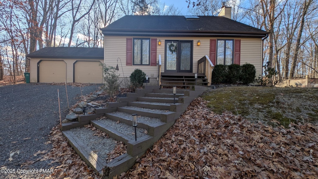 view of front of home featuring an attached garage, a chimney, and driveway