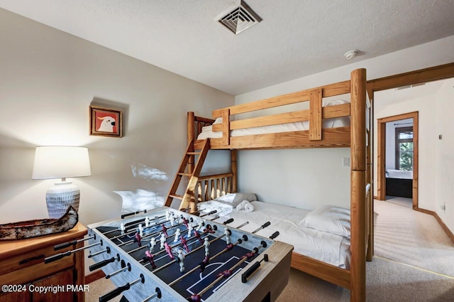 carpeted bedroom featuring a textured ceiling, visible vents, and baseboards