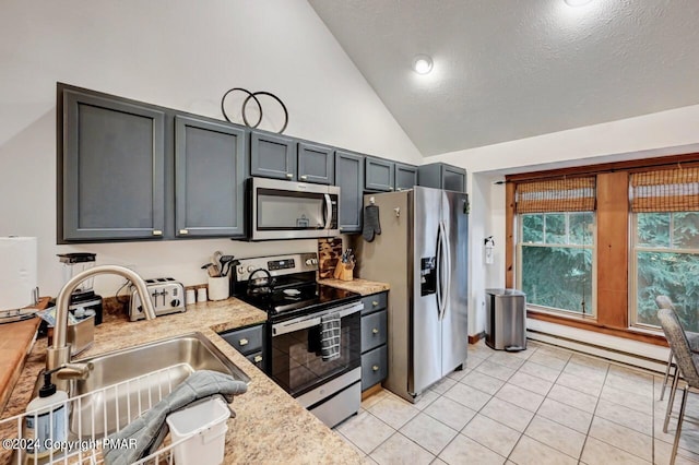 kitchen featuring light tile patterned floors, a baseboard heating unit, stainless steel appliances, a sink, and gray cabinets