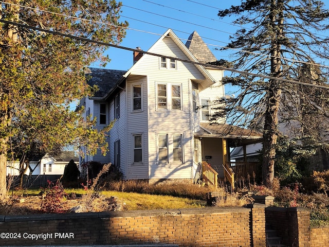 view of front facade featuring a chimney and fence