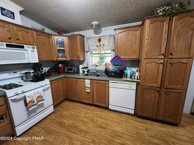 kitchen with a textured ceiling, white appliances, a sink, light wood-type flooring, and brown cabinetry