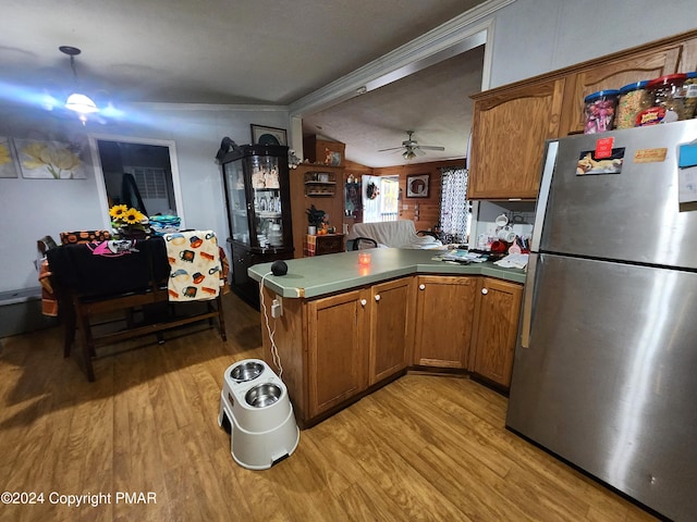 kitchen featuring a peninsula, brown cabinets, freestanding refrigerator, and light wood-style floors