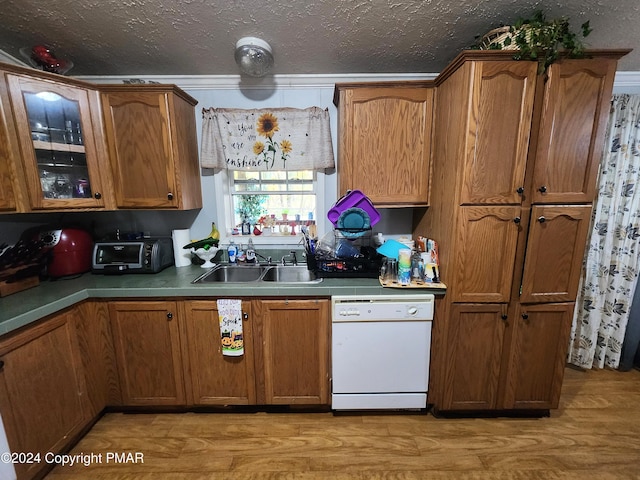 kitchen with brown cabinets, dishwasher, light wood-style flooring, and a sink