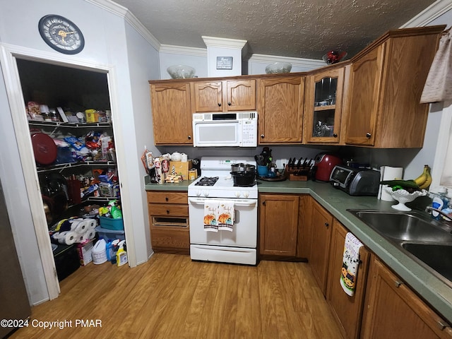 kitchen featuring white appliances, light wood-style flooring, brown cabinets, crown molding, and a textured ceiling