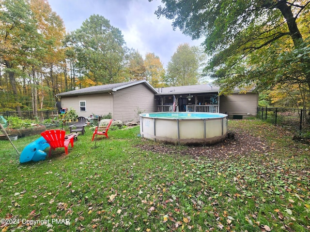 rear view of house with a yard, fence, and a fenced in pool