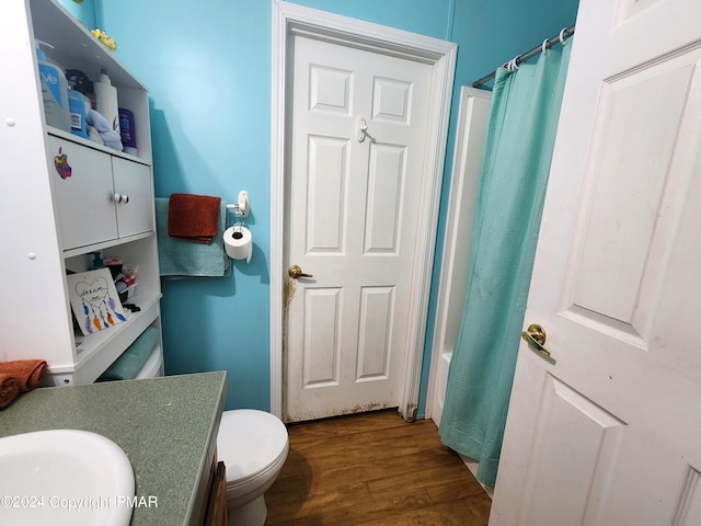 bathroom with curtained shower, toilet, wood finished floors, vanity, and a tub