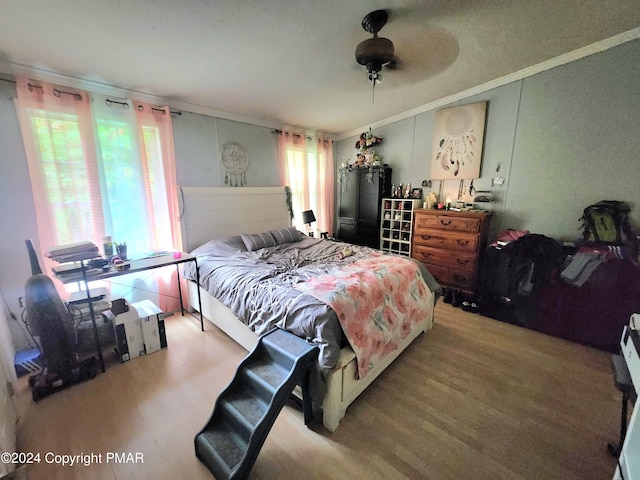 bedroom featuring ceiling fan, crown molding, and wood finished floors