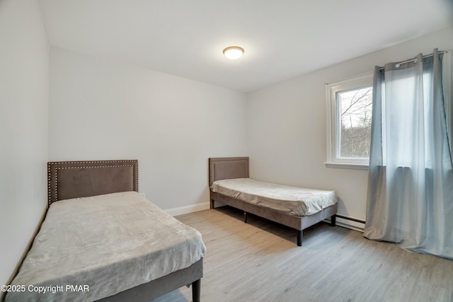 bedroom with light hardwood / wood-style flooring and baseboard heating