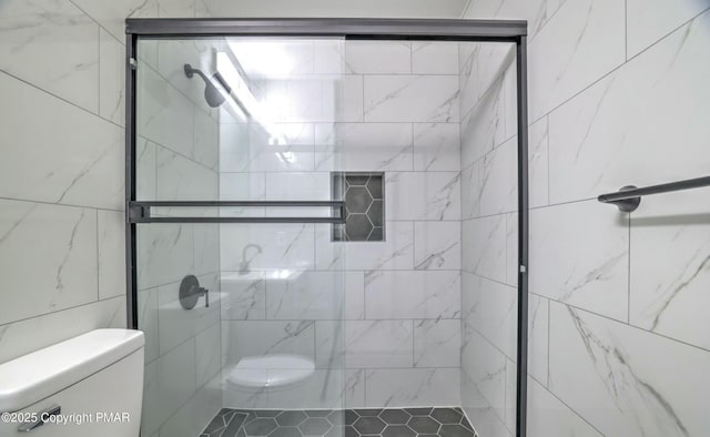 bathroom featuring toilet and a shower with shower door