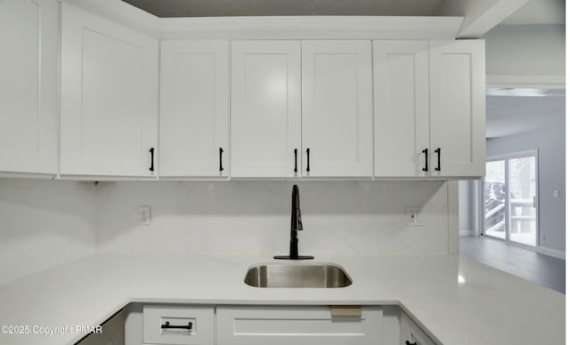 kitchen featuring sink, white cabinets, and backsplash