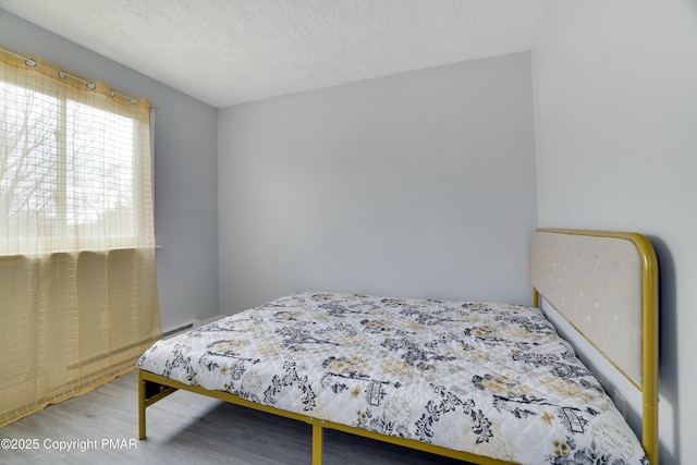 bedroom with hardwood / wood-style floors and a textured ceiling