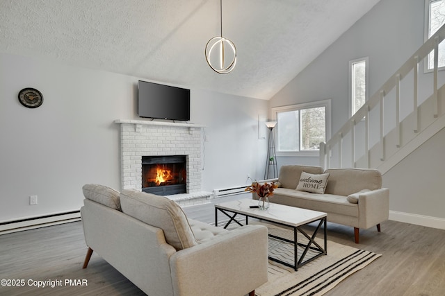 living room featuring a baseboard heating unit, hardwood / wood-style floors, a textured ceiling, and a fireplace