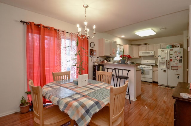 dining room featuring light wood finished floors, a notable chandelier, and visible vents