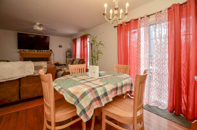 dining space featuring ceiling fan with notable chandelier and wood finished floors